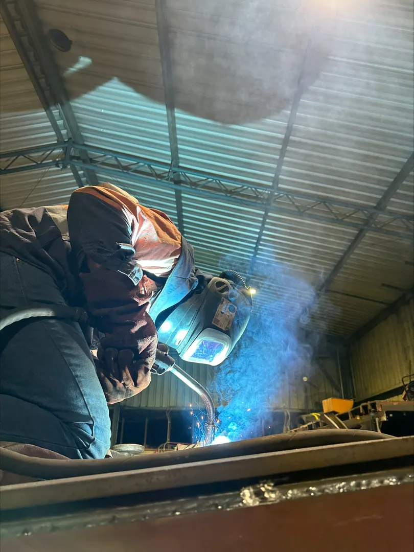 Welder working with sparks in industrial workshop.